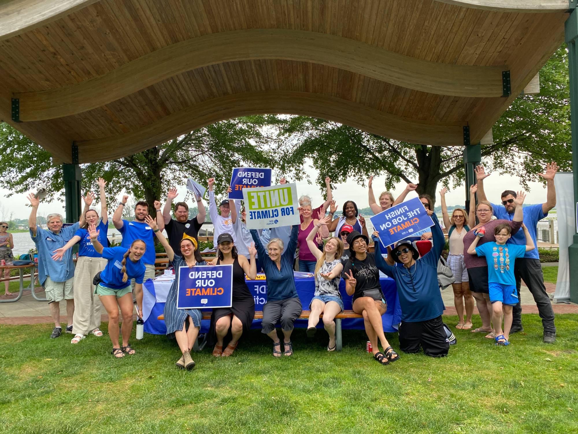 Attendees holding climate change action signs in front of the river in Spring Lake, Michigan.